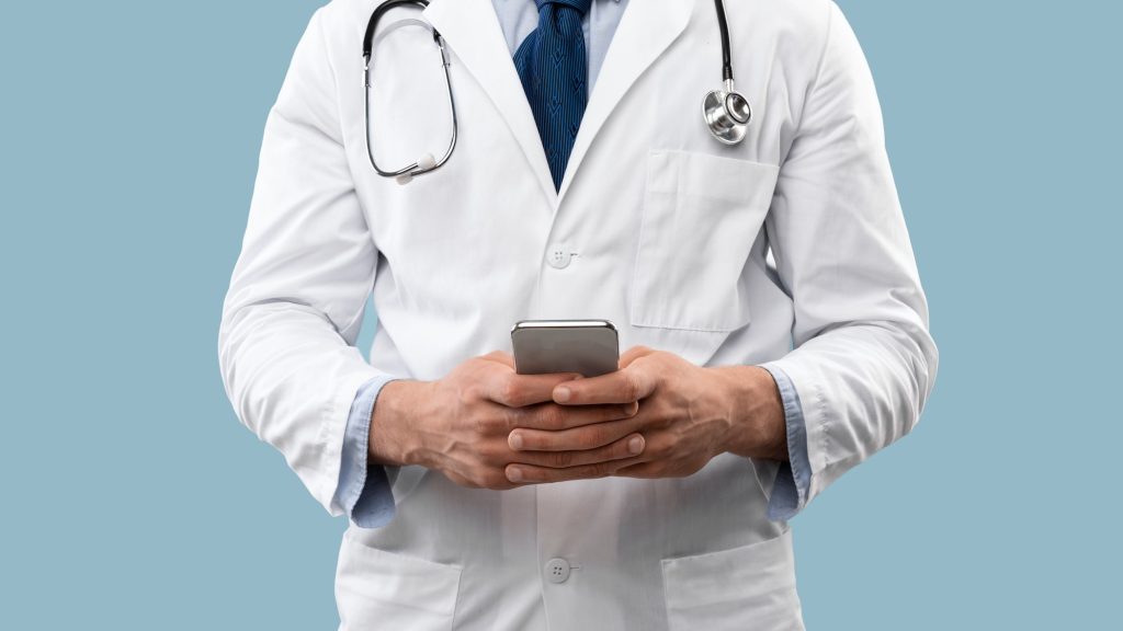 Cropped Shot Of Doctor Man Using Smartphone Over Blue Background